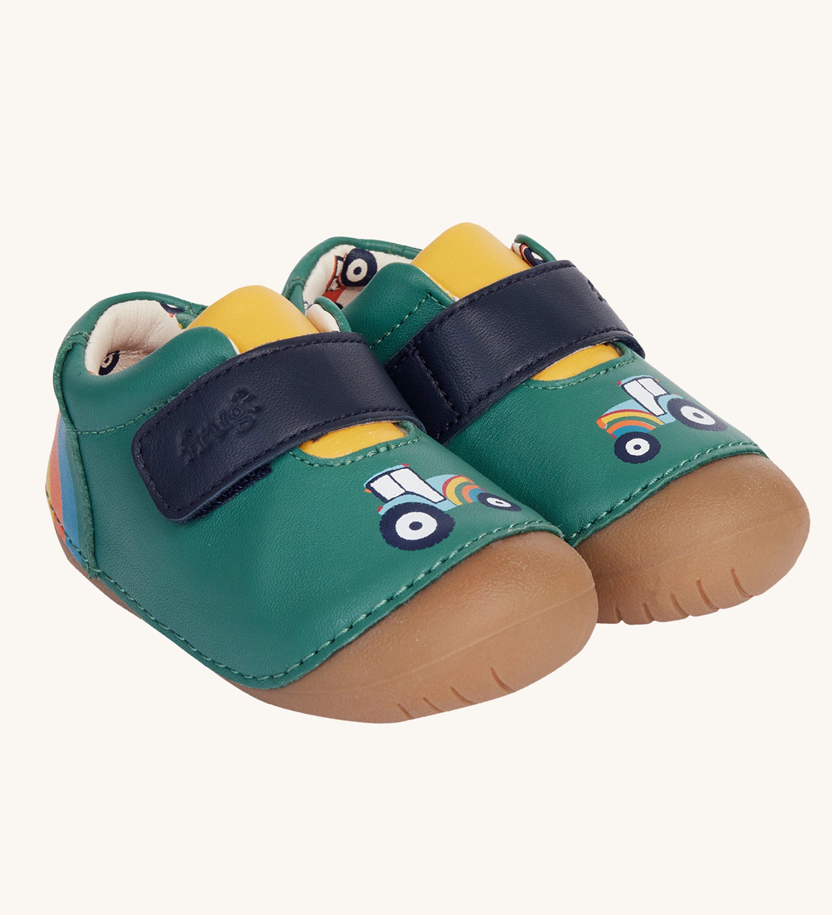 The Fjord First Walker leather baby shoes in a holly green colour have a tractor design on the front and a rainbow design on the back. The leather lining has a cream background with a colourful tractor print inside.