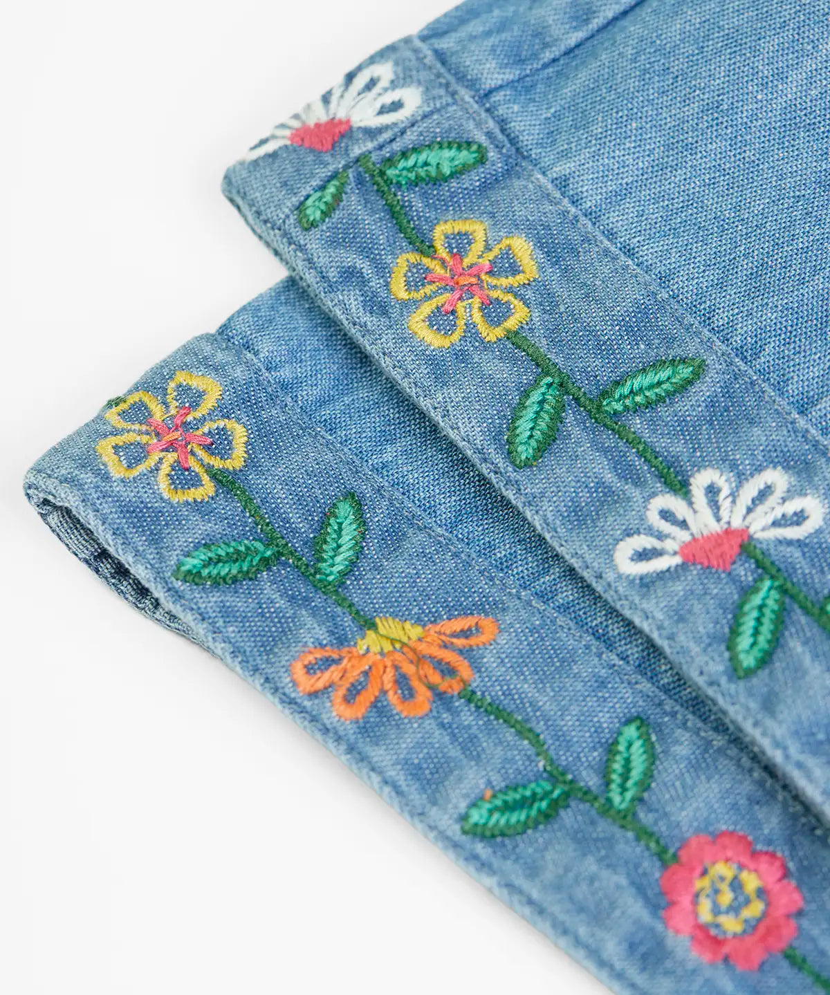 Close up of the embroidered flowers on the cuffs of the Frugi flared organic denim dungaree.
