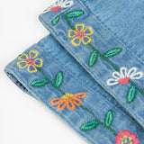 Close up of the embroidered flowers on the cuffs of the Frugi flared organic denim dungaree.