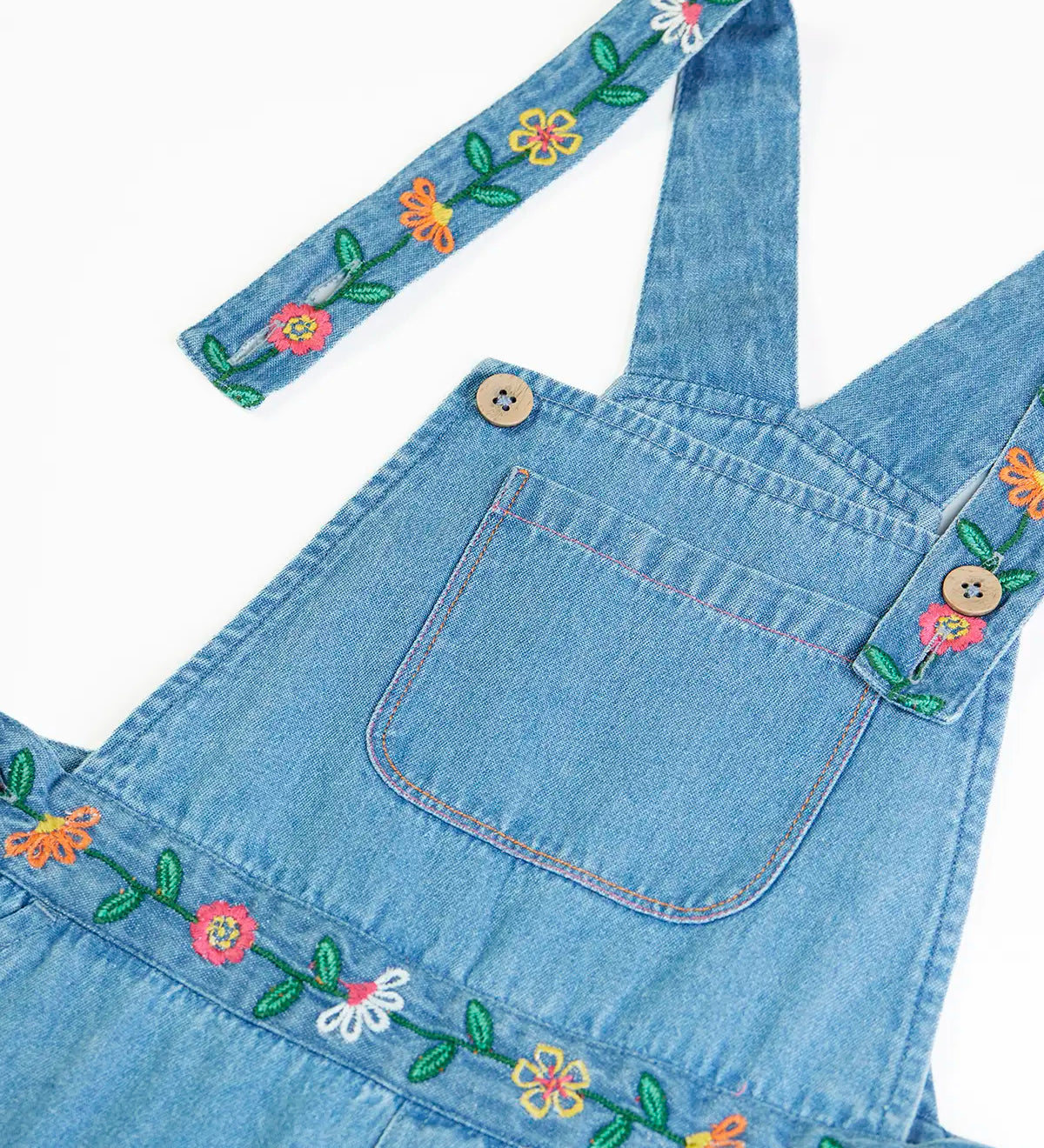 Close up of the button closure straps on the Frugi flared denim dungaree with embroidered flower design.