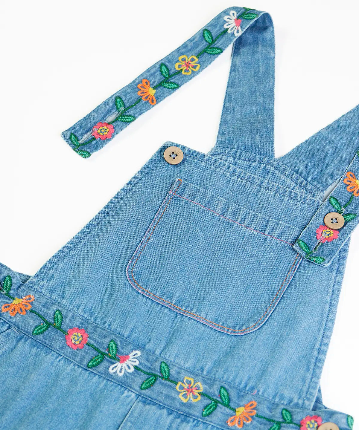 Close up of the button closure straps on the Frugi flared denim dungaree with embroidered flower design.
