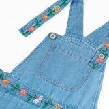 Close up of the button closure straps on the Frugi flared denim dungaree with embroidered flower design.
