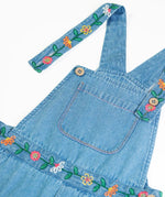 Close up of the button closure straps on the Frugi flared denim dungaree with embroidered flower design.
