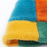A close up of the Frugi kids fleece bucket hat in hotchpotch showing the multicoloured block detail on 100% recycled polyester fabric.