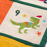 Close up of day 9 pocket featuring a t-rex dinosaur wearing a santa hat on the  Frugi forest festive fun organic cotton advent calendar. 
