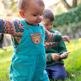 A child wearing the Frugi fowey bear fairisle organic cotton knitted jumper. underneath a pair of boat coloured, blue bear durgan cord dungarees.
