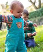 A child wearing the Frugi fowey bear fairisle organic cotton knitted jumper. underneath a pair of boat coloured, blue bear durgan cord dungarees.