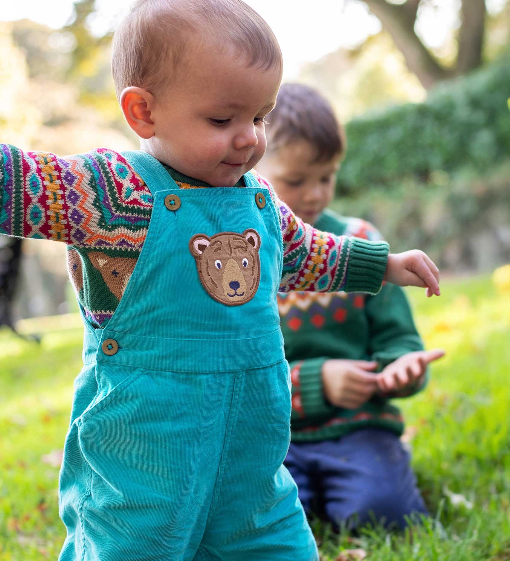 A child wearing the Frugi fowey bear fairisle organic cotton knitted jumper. underneath a pair of boat coloured, blue bear durgan cord dungarees.