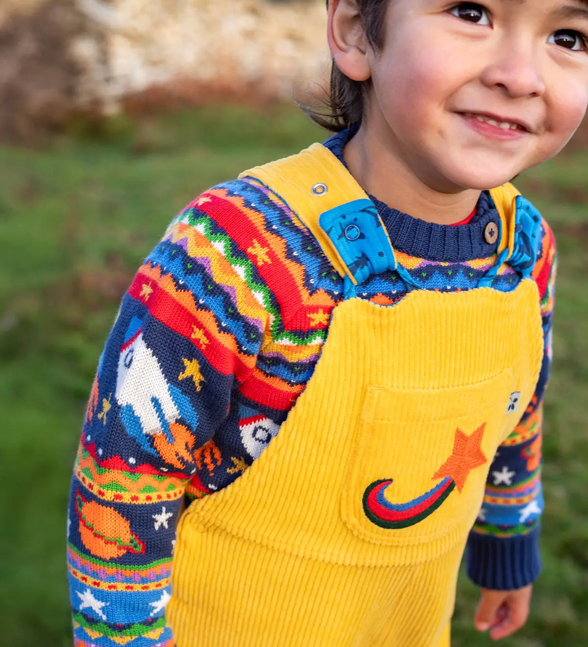 Child wearing a yellow cord dungarees with Frugi Fowey Fairisle Knitted Jumper Space Fair Isle underneath.