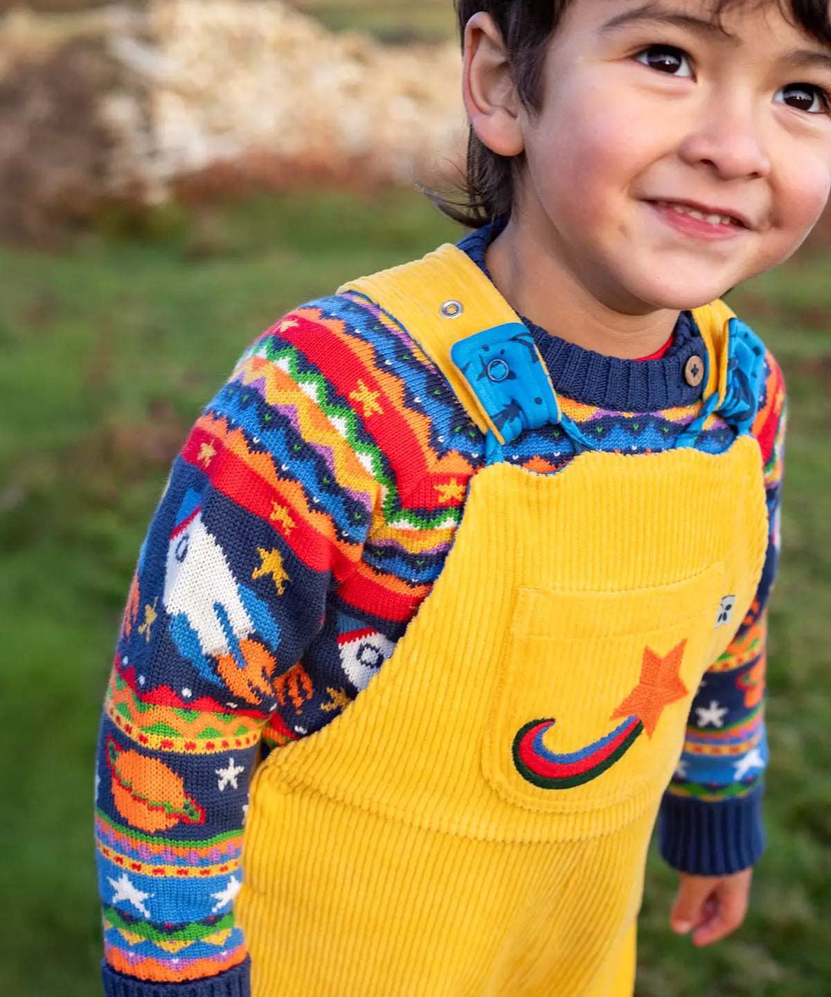 Child wearing a yellow cord dungarees with Frugi Fowey Fairisle Knitted Jumper Space Fair Isle underneath.