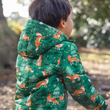 A child wearing the Frugi toasty trail reversible jacket showing the playful fox in woodland design and hood detail on green post consumer recycled polyester fabric