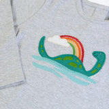 Close up of the loch ness monster applique on the front of the Frugi frankie organic cotton baby and toddler outfit with Nessie design. Long sleeved grey marl top with wide orange stripe trousers. 