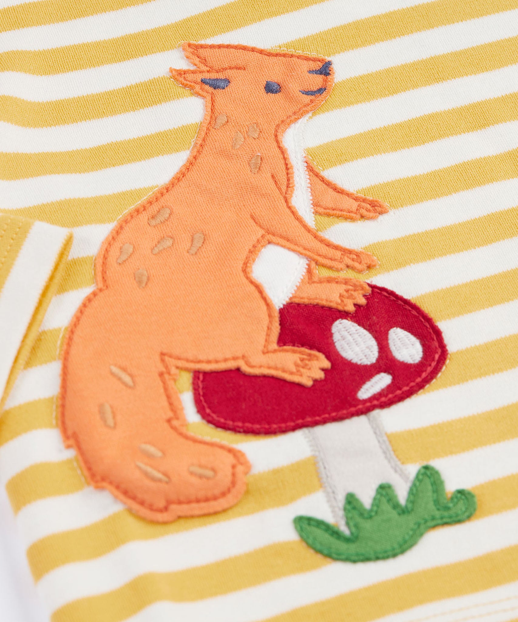 A close up of the squirrel applique on the front of the long sleeved top from the Frugi Frankie Outfit with a bumblebee yellow stripe and squirrel friends design. 
