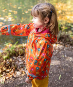 A side view of a toddler wearing the Frugi fun flowers puddle buster coat showing the hood detail and pink fleece inside liner. 