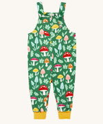 Frugi fun guys print dungarees. The Fun guys print features multi-coloured mushrooms and light green leaves on a dark green background. The dungarees have yellow gold coloured leg cuffs for extended wear.