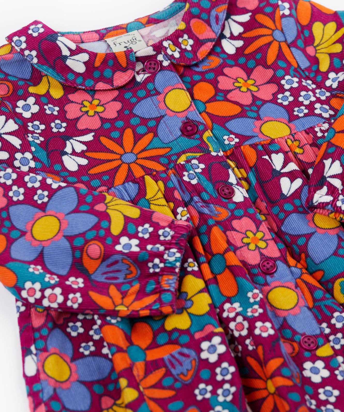 A close up of the Frugi Organic Cotton Chloe Corduroy Dress for Babies and Toddlers featuring a Retro Floral print design. This dress is a part of a wide range of organic cotton clothing for children available here at Babipur.