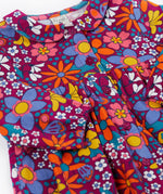 A close up of the Frugi Organic Cotton Chloe Corduroy Dress for Babies and Toddlers featuring a Retro Floral print design. This dress is a part of a wide range of organic cotton clothing for children available here at Babipur.