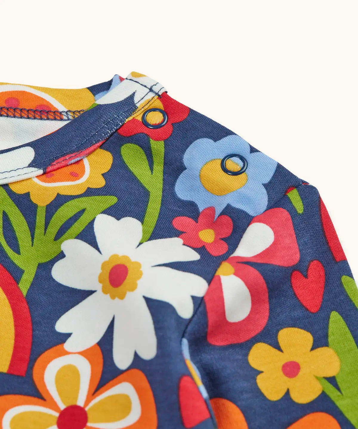Close up of the popper closure on the shoulder of the Frugi goldie long sleeve organic cotton top in navy with an all over beautiful bunch flowers print.