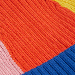 A child wearing the Frugi Children's Rainbow Rib Bobble Hat - Blue Tang/Rainbow