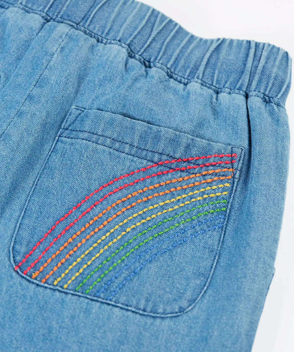 Frugi GOTS organic cotton denim trousers showing close up of a rainbow embroidery design on the back pocket and elasticated waist band