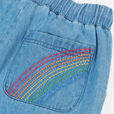Frugi GOTS organic cotton denim trousers showing close up of a rainbow embroidery design on the back pocket and elasticated waist band