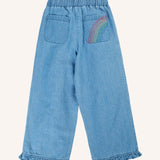 Back of Frugi grace denim trousers with rainbow embroidery design o none of the back pockets and ruffle hem cuffs on the legs,