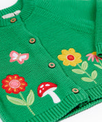 A close up of the flower, butterfly and mushroom appliques on the front of the Frugi colby clover green coloured knitted organic cotton cardigan.