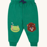 Frugi holly green coloured frog beaver crawlers kids organic cotton joggers. One knee has a frog applique the other knee has a beaver.