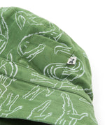 A close up of the Frugi kids green crocodile reversible hat. Showing the little pocket detail on the side of the hat surrounded by the white outlined crocodile design on green organic cotton fabric