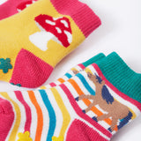 Frugi kids organic cotton grippy socks featuring wild woods designs.  One pair is rainbow striped with a horse and yellow flower grips. The other pair features a mushroom design with green flower grips, one sock is yellow one is pink.