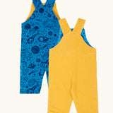 Back of the Frugi Gylly cord reversible dungaree in bumblebee yellow with star pocket design on one side and blue all over monochrome space print on the other.