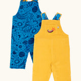 Frugi Gylly cord reversible dungaree in bumblebee yellow with star pocket design on one side and blue all over monochrome space print on the other.