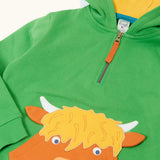 Close up of the front of the Frugi Hadley half zip hoodie in palm green with a highland cow applique on the front that incorporates a kangaroo pocket.