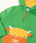 Close up of the front of the Frugi Hadley half zip hoodie in palm green with a highland cow applique on the front that incorporates a kangaroo pocket.