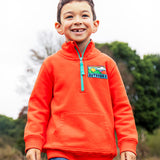 A child wearing the Frugi Half Zip Organic Cotton Papaya orange Jumper with large Outdoors colour block style graphic on the chest.