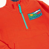 A close up of the front of the Frugi Half Zip Organic Cotton Papaya orange Jumper with large Outdoors colour block style graphic.