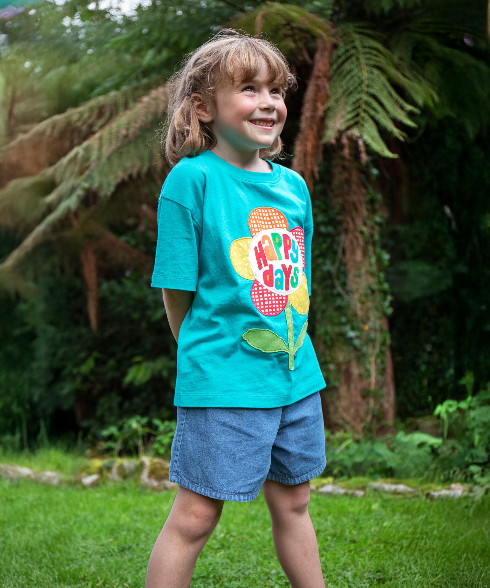A child wearing the Frugi  Happy Days Mabe Relaxed T-Shirt with denim shorts 