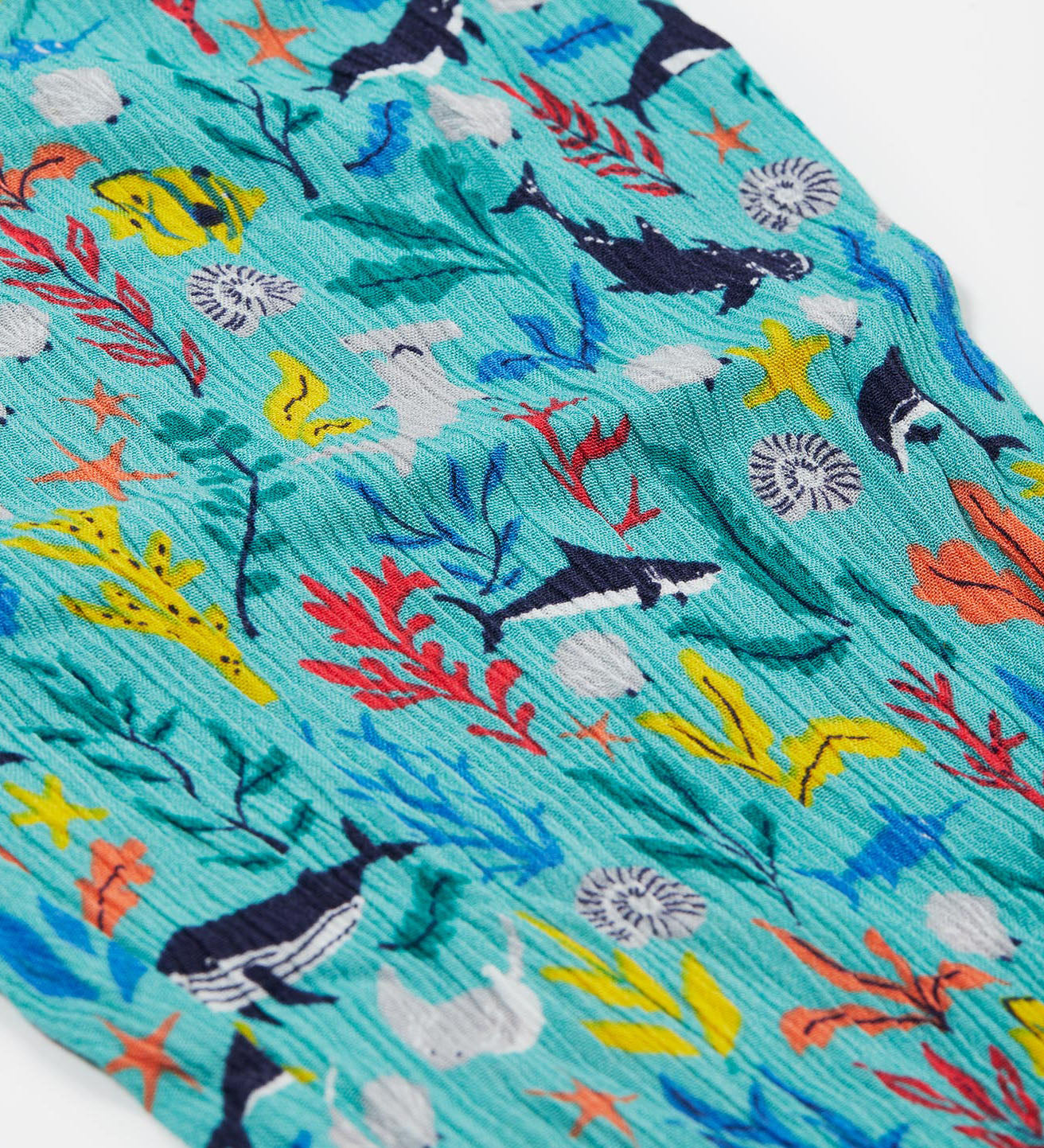 A close up of Frugi Eira Harems, featuring a Sea Life print which includes different sea animals and colourful seaweed and coral on a mint blue background.