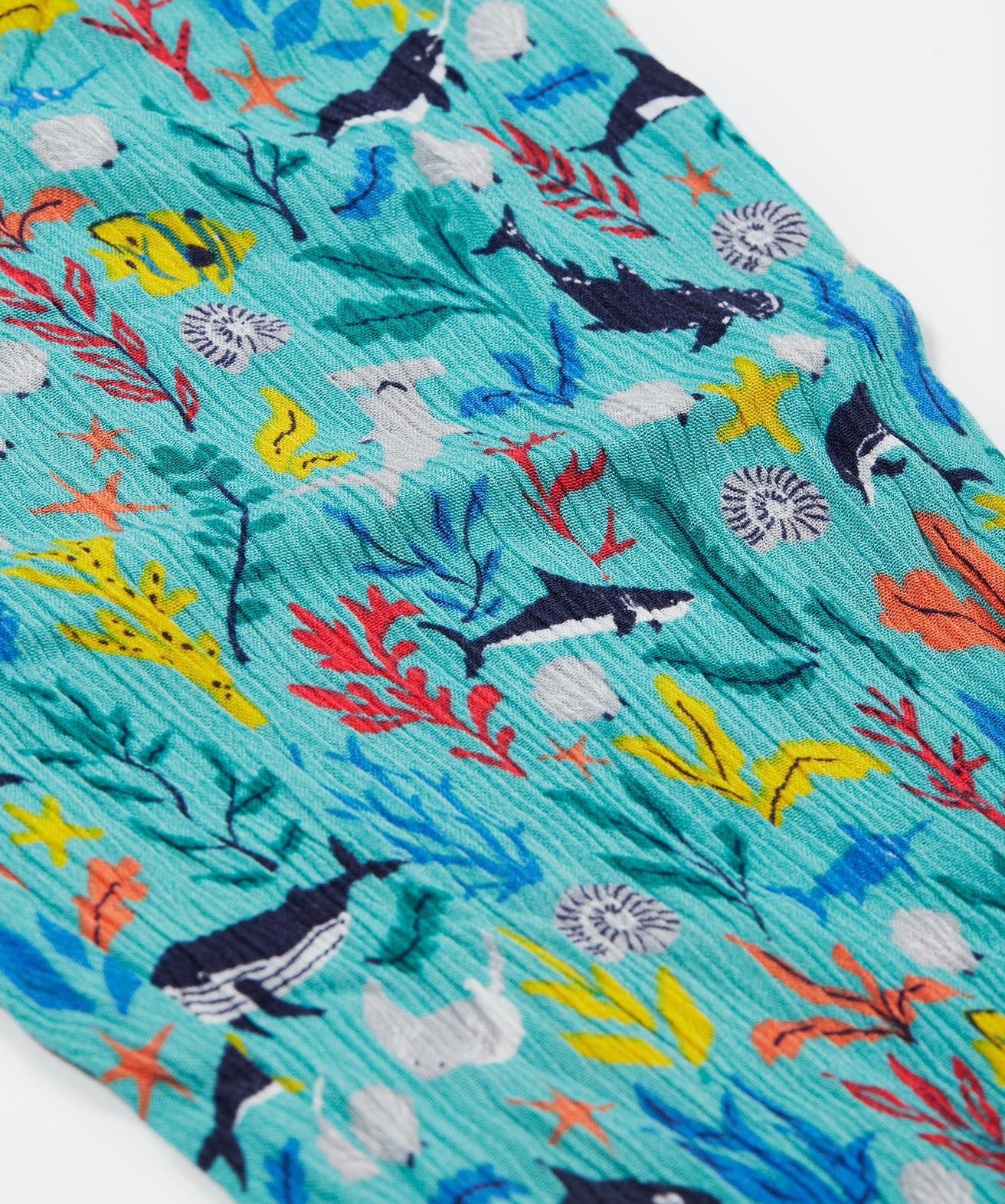 A close up of Frugi Eira Harems, featuring a Sea Life print which includes different sea animals and colourful seaweed and coral on a mint blue background.