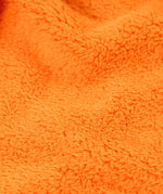 Close up of the orange recycled polyester fleece on the Frugi Helston reversible hoodie jacket. One side is navy cotton with a hello badge design on the chest  with a orange fleece body and yellow sleeves on the other.
