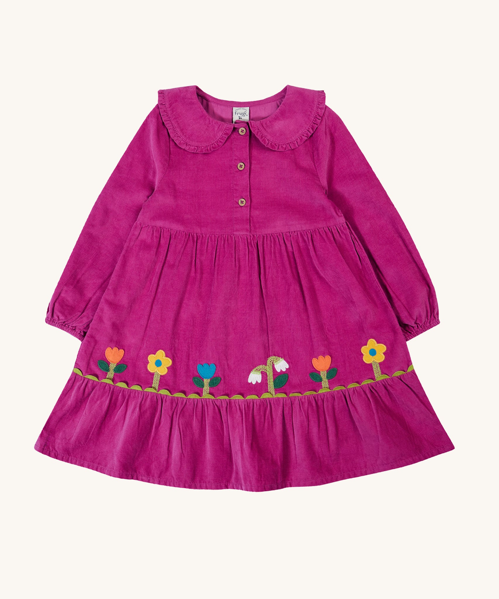 Frugi kids holly dress in damson flowers available at Babipur. A 100% GOTS organic cotton corduroy dress in bright purple with flower appliques on the skirt. Features a frilled collar and button fasteners. 