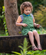A child wearing the Frugi Pentire hotpotch pocket t-shirt, a soft GOTS organic cotton top with orange and blue stripes and a light blue neck trim. 