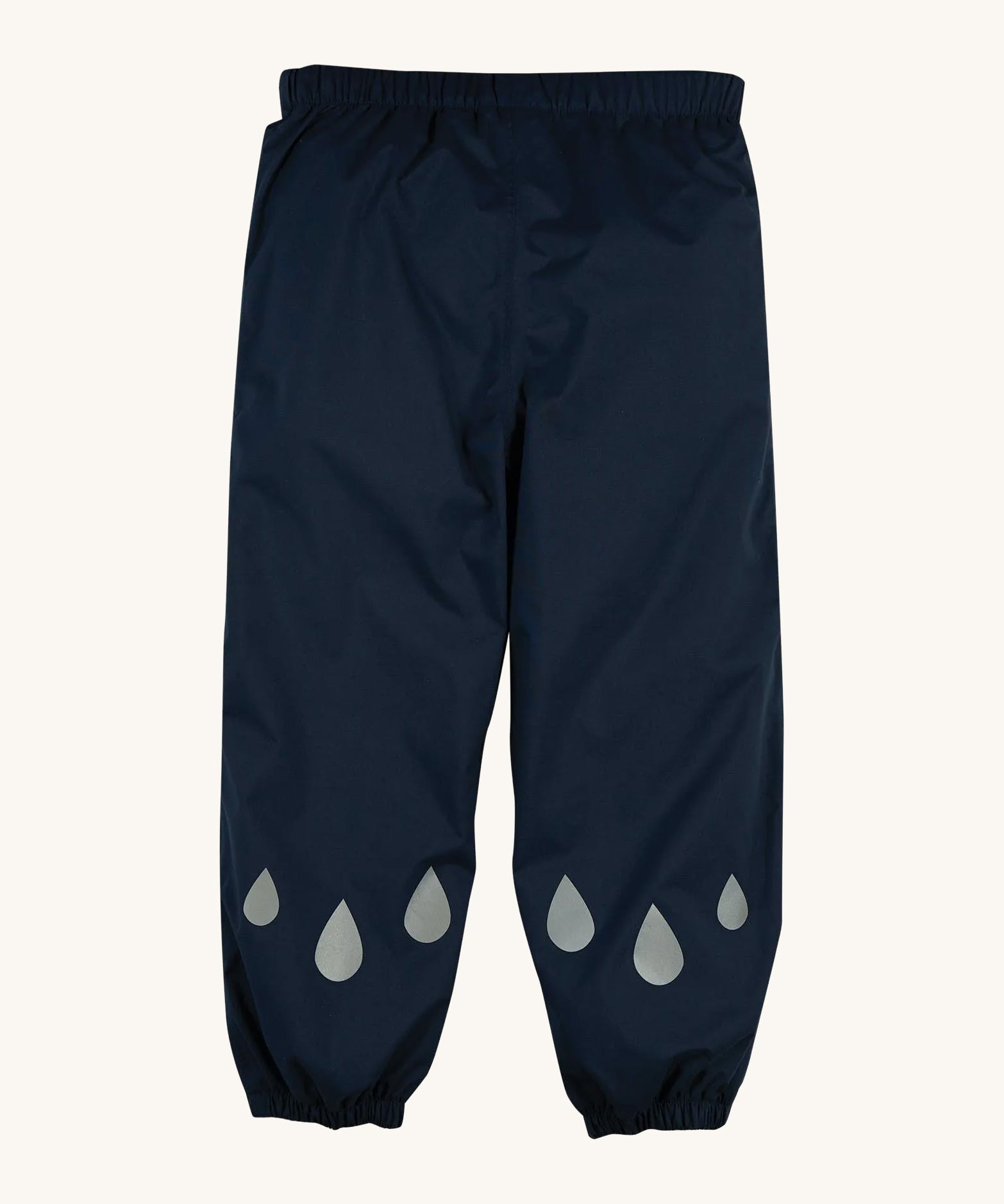 The front of the Frugi Indigo Navy coloured Rain Or Shine waterproof Trousers. The trousers have rain drop shaped reflective patches on the lower leg.