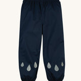 The front of the Frugi Indigo Navy coloured Rain Or Shine waterproof Trousers. The trousers have rain drop shaped reflective patches on the lower leg.