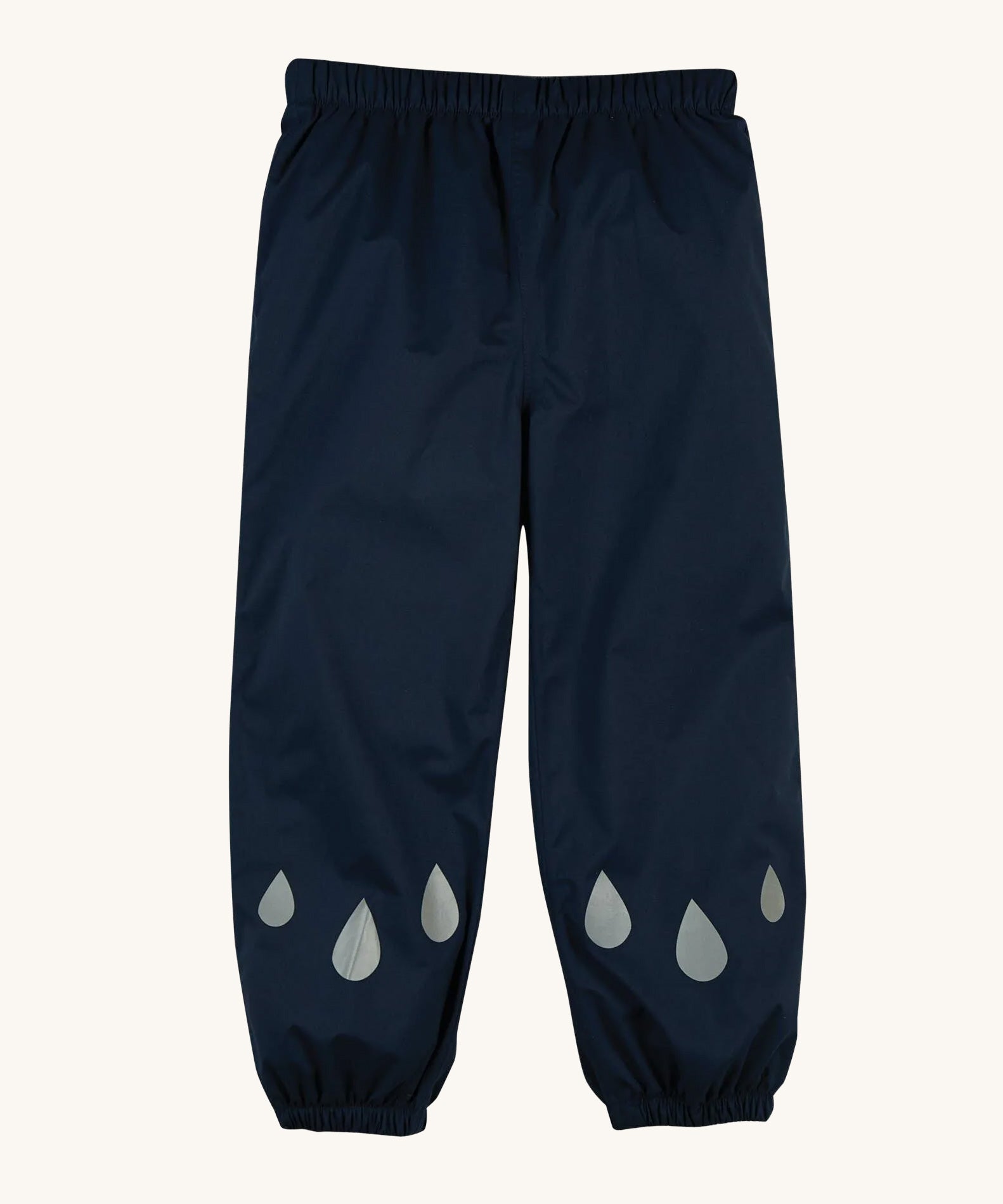 The front of the Frugi Indigo Navy coloured Rain Or Shine waterproof Trousers. The trousers have rain drop shaped reflective patches on the lower leg.