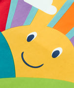 A close up of the yellow smiley sunshine graphic on the front of the Frugi organic cotton lichen green t-shirt.