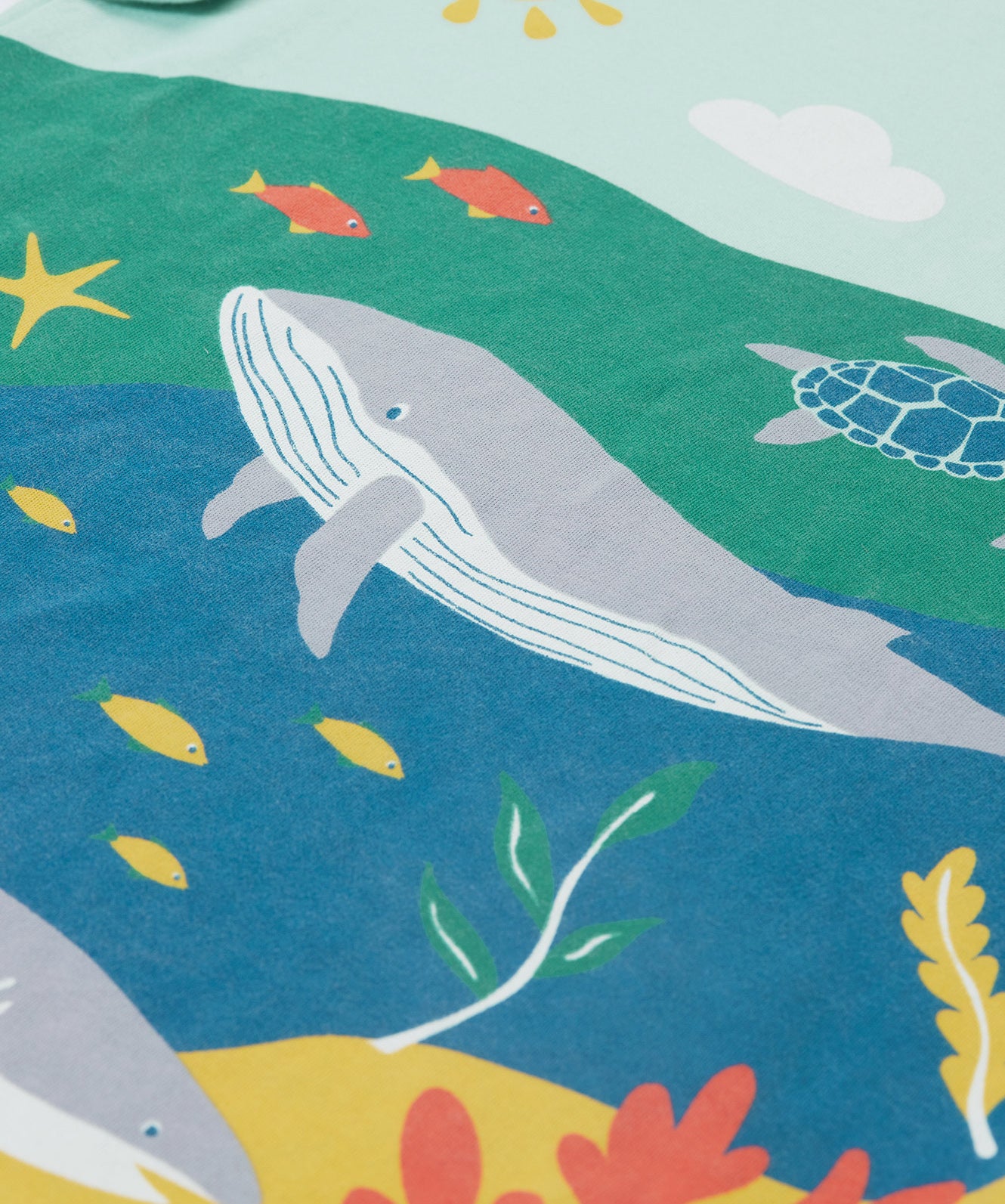 A close up of Frugi Iori Printed T-Shirt in Spring Mint's colourful Sea Life Scene which includes whales and other smaller fish and coral. 
