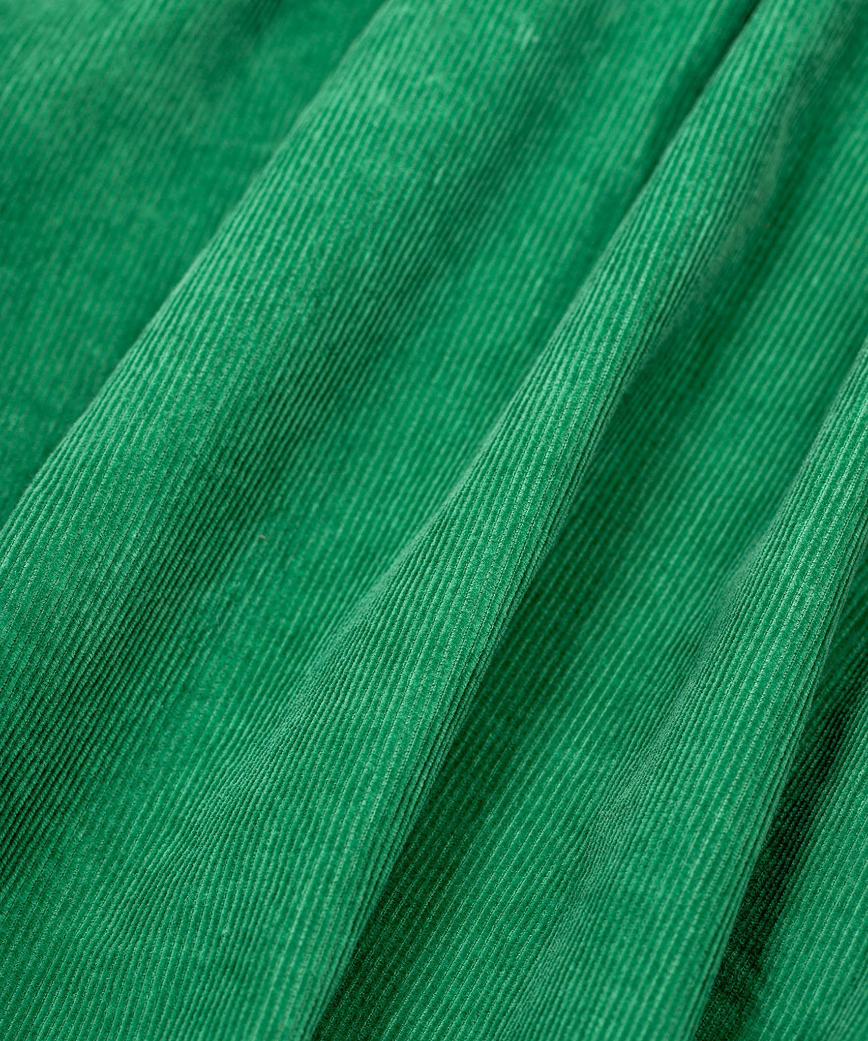 A close up of the frugi kids isla dugaree dress in holly green/mushroom showing the corduroy detail on green organic cotton fabric.