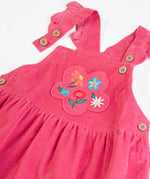 Close up of the front showing the frilled edge straps of the Frugi Isla pink rose dungaree dress with flowers embroidery on the front.