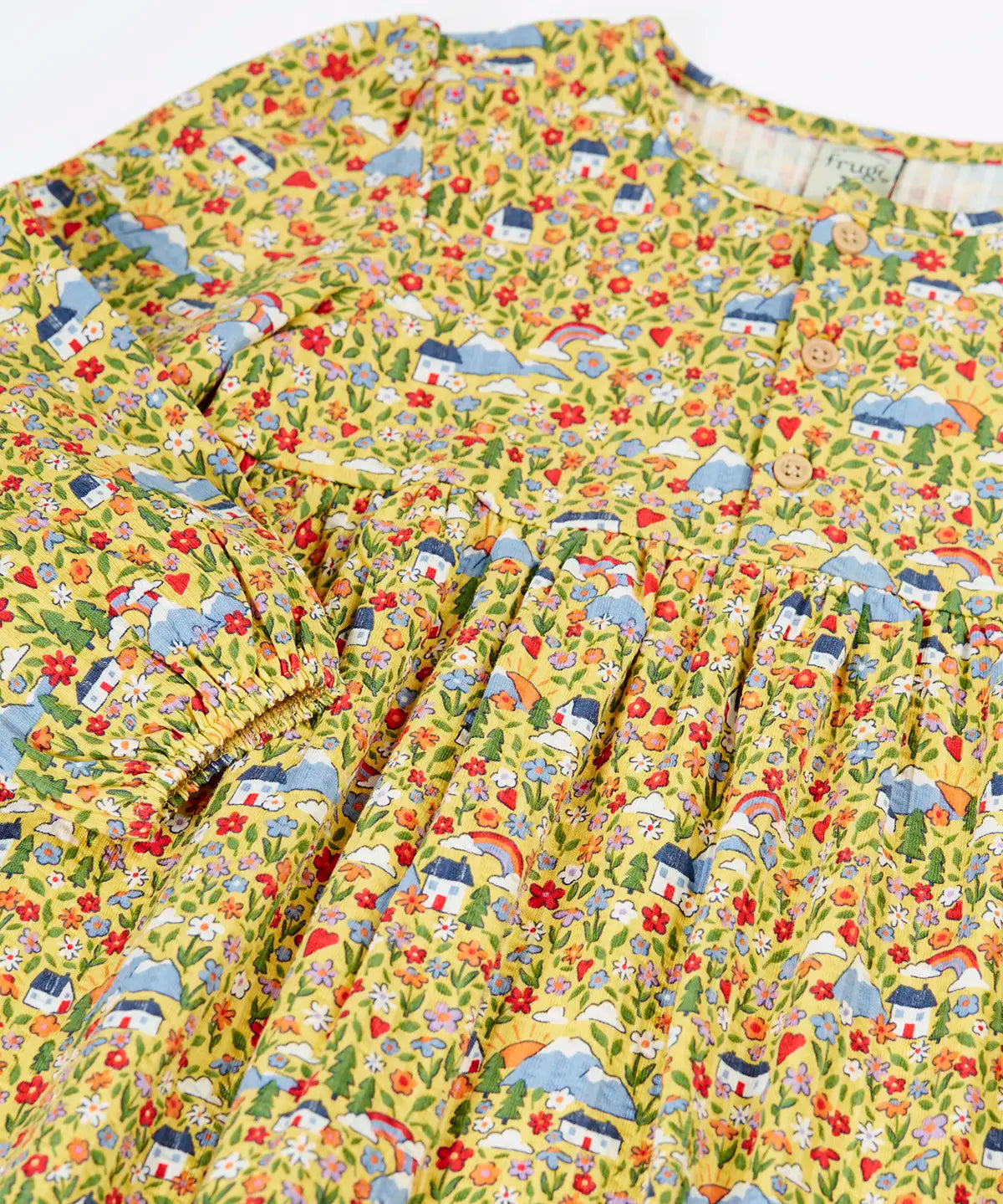 Close up of the elasticated cuffs on the Frugi Izzie organic cotton jersey dress with highland houses print on a yellow background. 